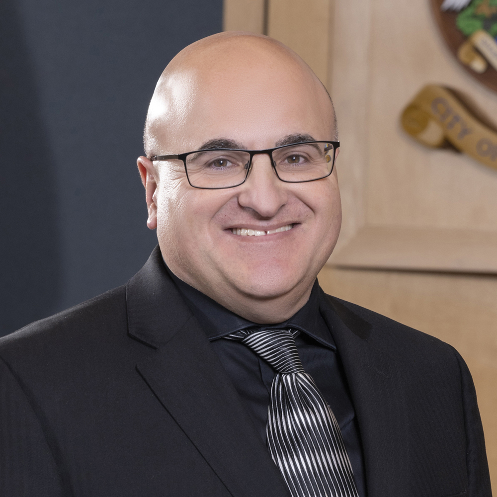 Headshot of Councillor Ron Polillo in council chambers, with City of Prince George crest partially visible in background.